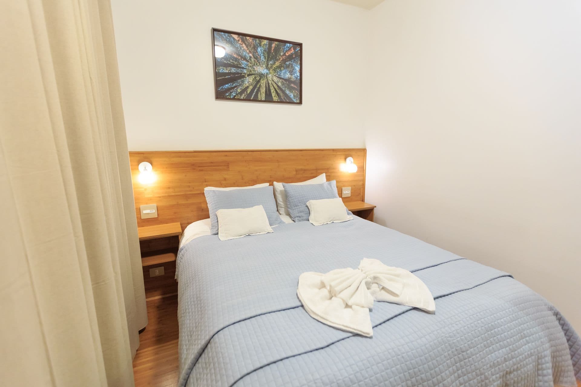 Compact double bedroom with a timber headboard and blue linen
