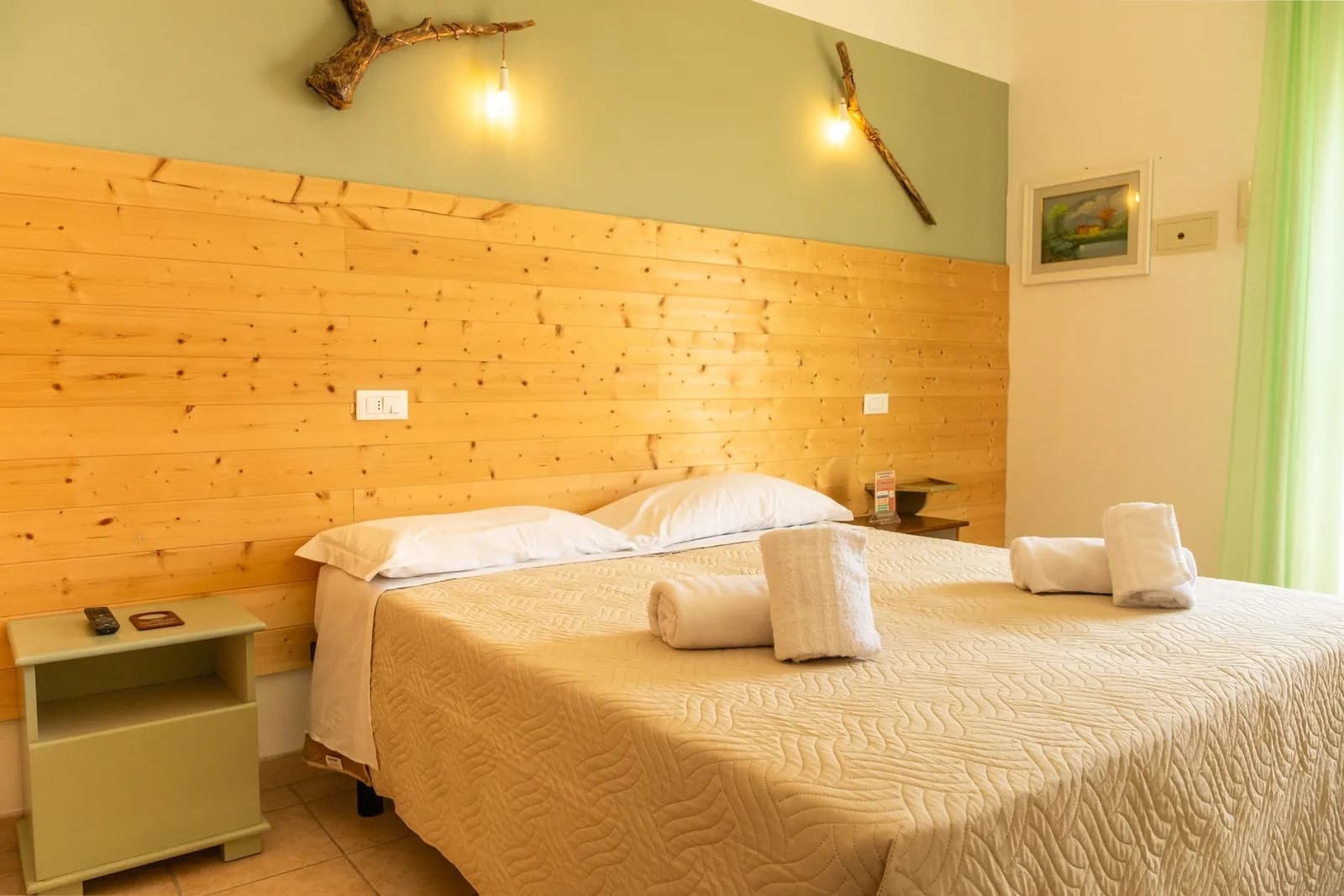 Double bedroom with a pine-panelled wall and folded towels