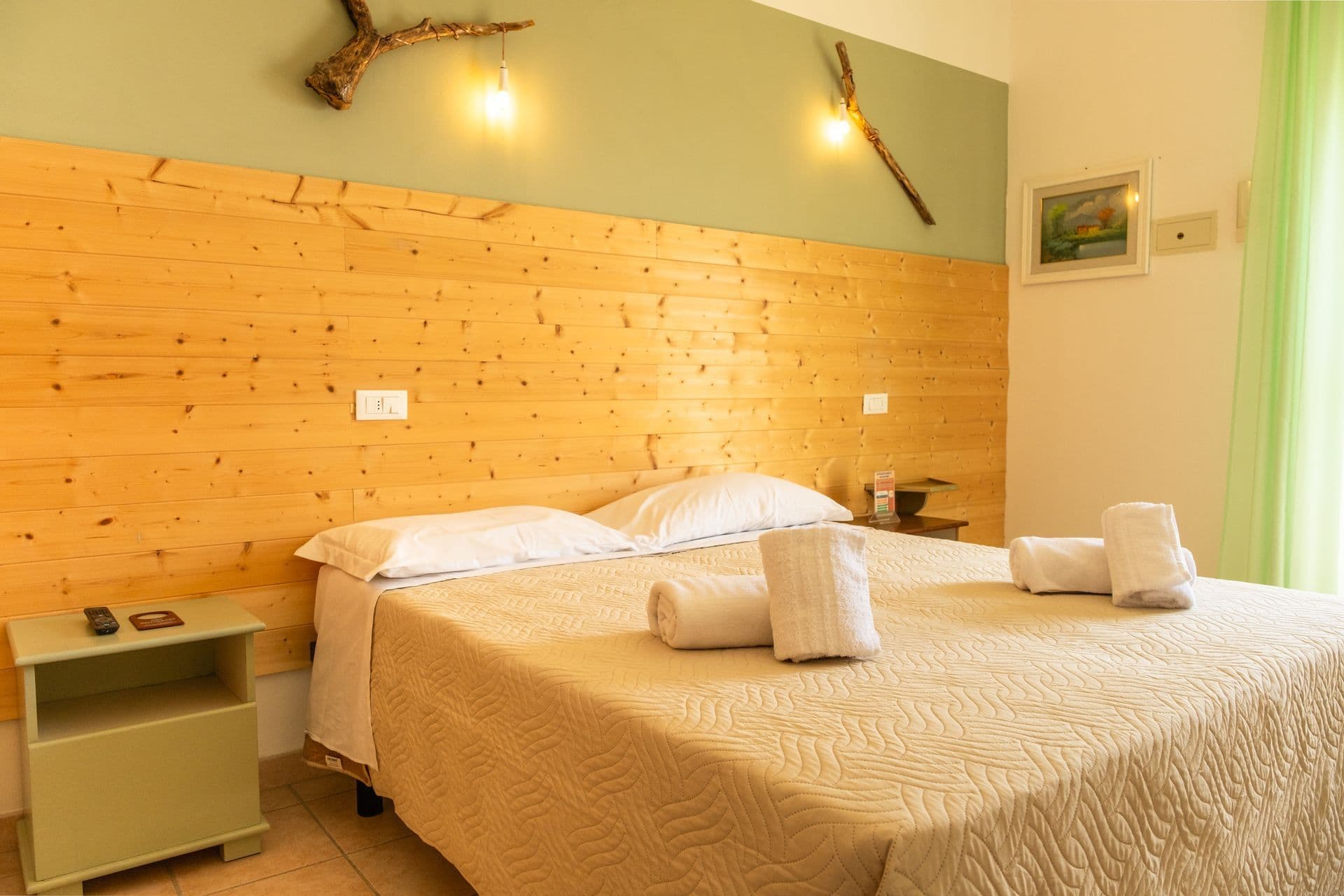 Double bedroom with a pine-panelled wall and folded towels
