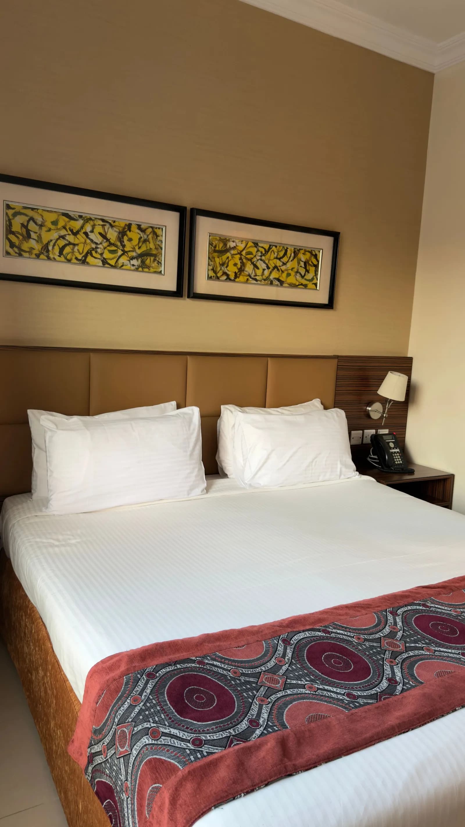 Double bedroom with a tan headboard and two framed abstract prints