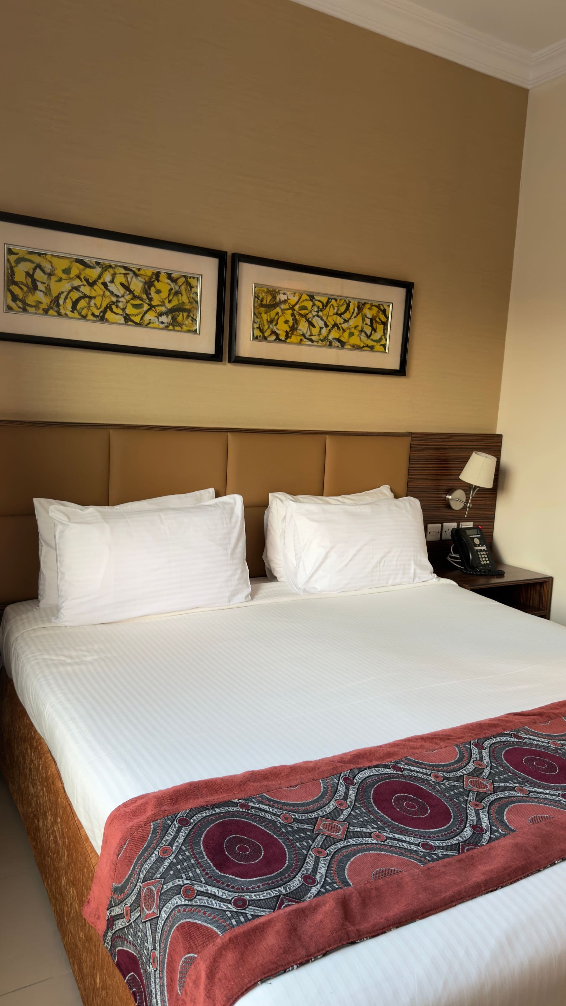Double bedroom with a tan headboard and two framed abstract prints