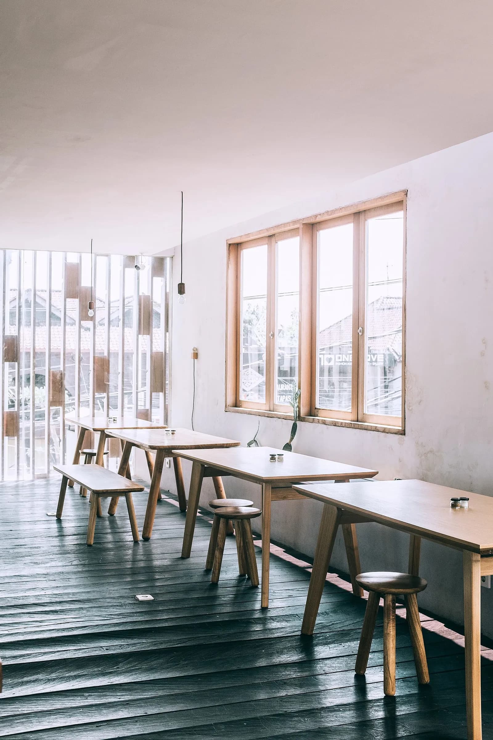 Cafe with wooden tables and stools beside tall windows