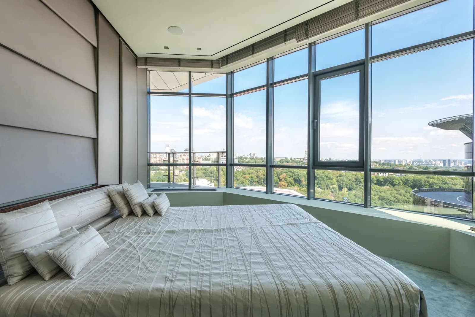 Bedroom with a low wide bed beside a floor-to-ceiling corner window