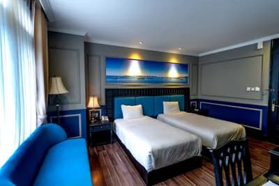 Twin room with blue headboards, a blue sofa and a wide landscape artwork