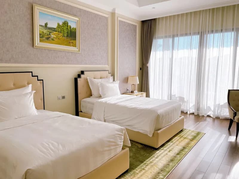 Bright twin room with cream headboards and a landscape painting