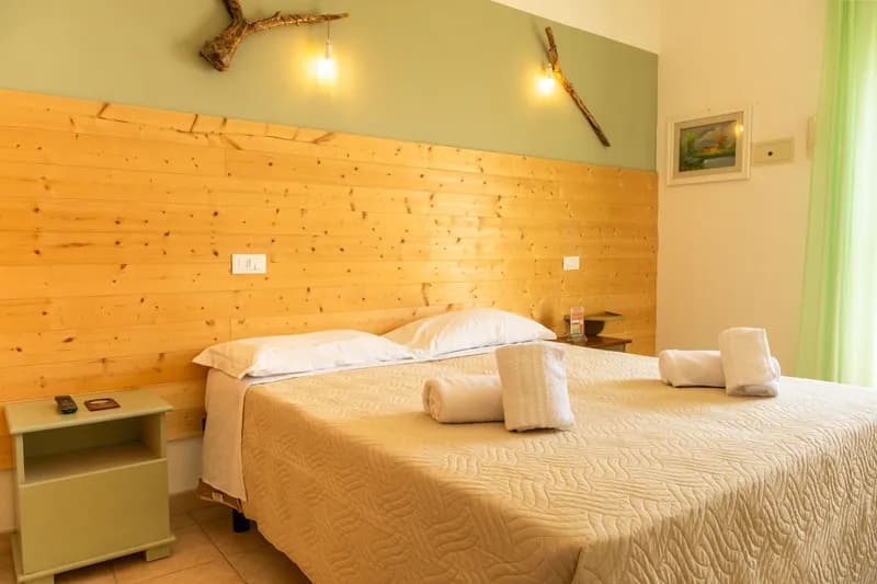 Double bedroom with a pine-panelled wall and folded towels