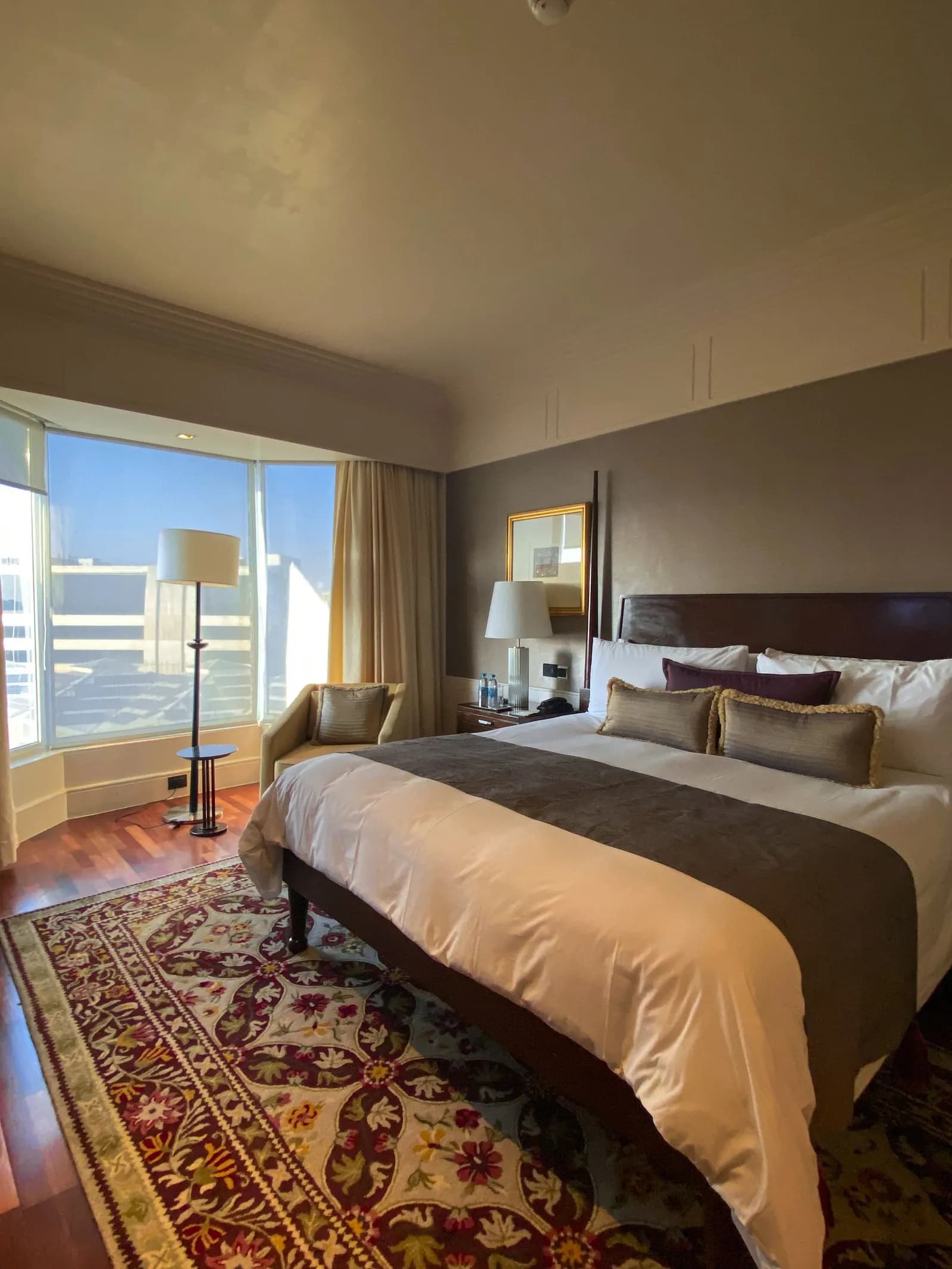 Bedroom with a dark headboard, a patterned rug and a curved bay window