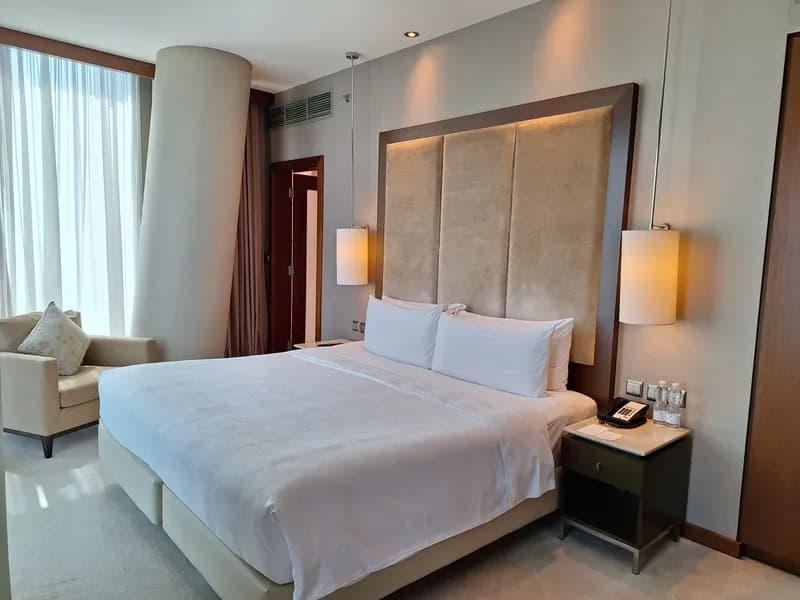 Bedroom with a tall padded headboard, an armchair and a round column
