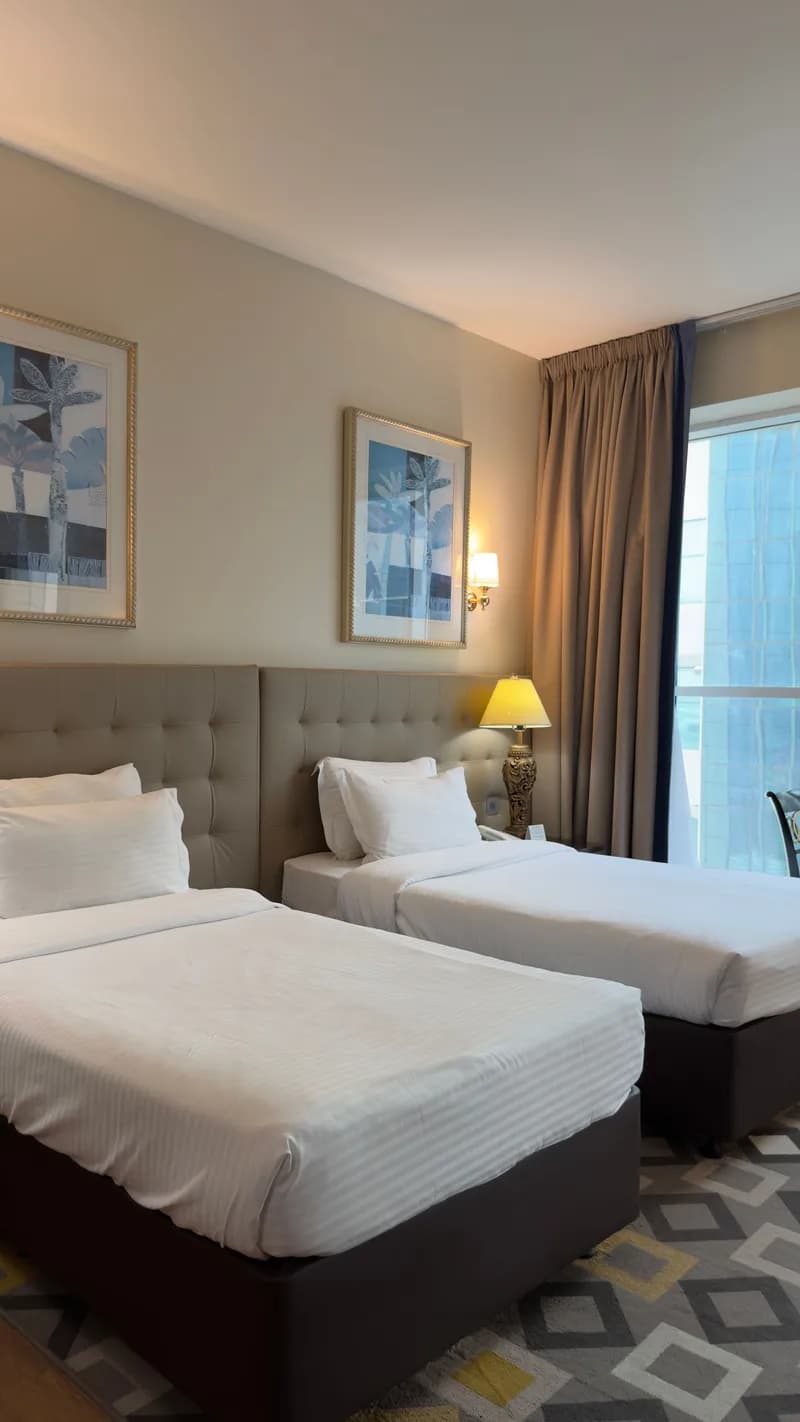 Twin room with grey padded headboards and framed tree prints