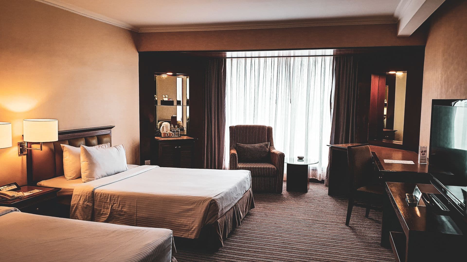Twin room with a writing desk, an armchair and tall curtains