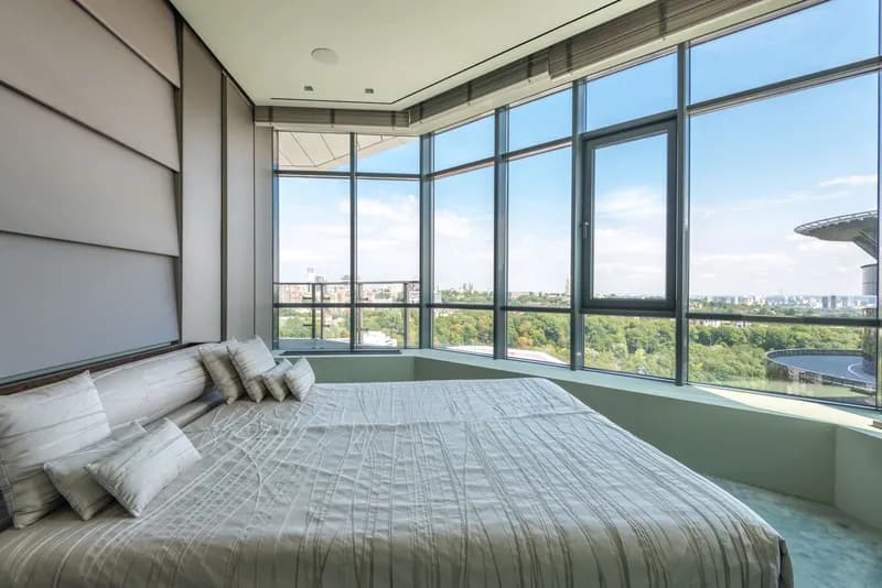 Bedroom with a low wide bed beside a floor-to-ceiling corner window