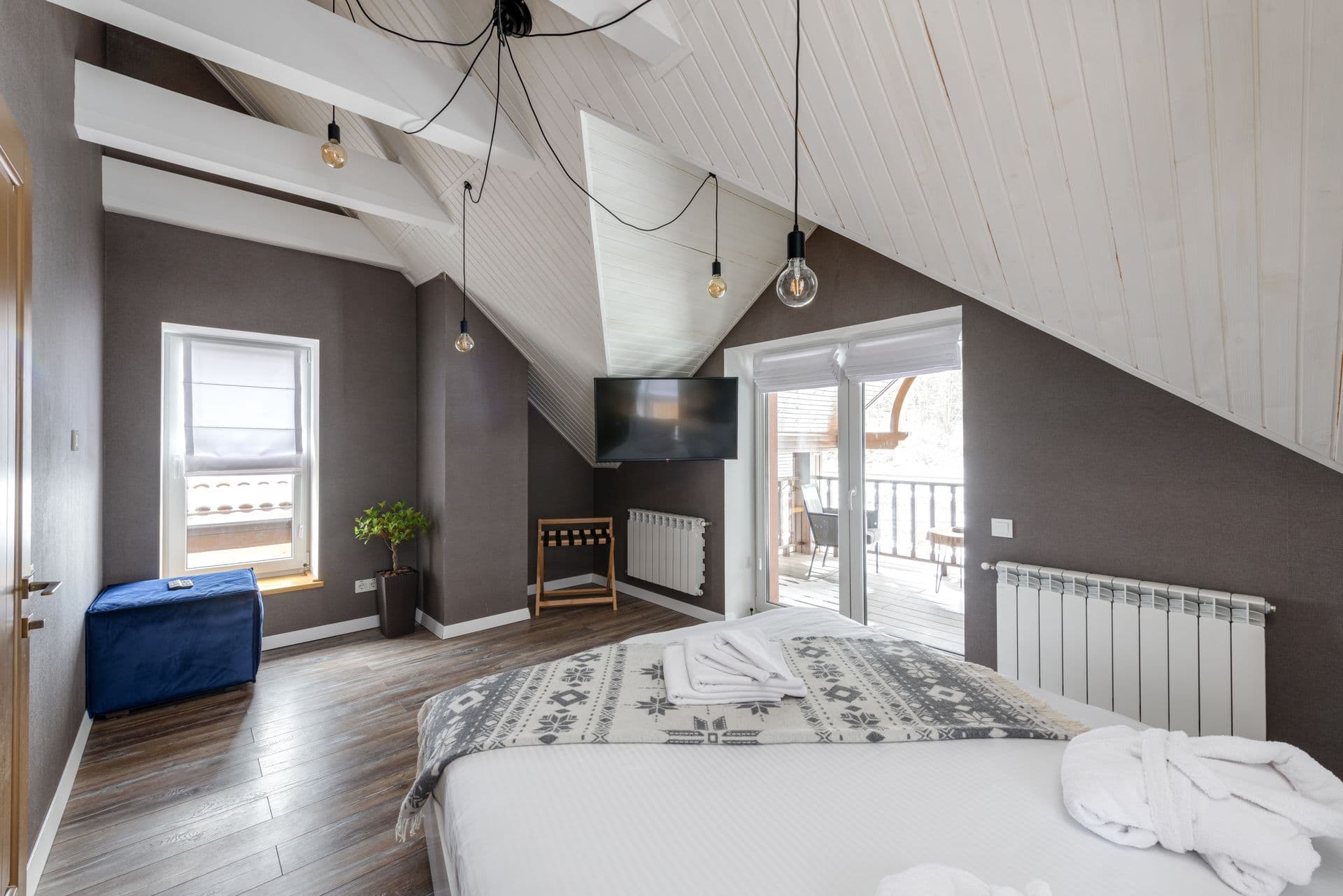 Bright bedroom with a sloping white ceiling and a glass balcony door